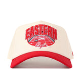 Introducing the No Rivals EWU Eagles Stadium Hat, featuring a beige performance fabric crown and a solid red brim. The hat showcases an embroidered Eastern Eagles logo in red and white above a running track graphic, all in a stylish snapback design.