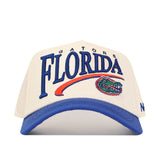 Introducing the Florida Gators Stride Hat by No Rivals—a stylish white and blue baseball cap featuring “Gators Florida” and the University of Florida Gators logo embroidered on the front. Designed with a structured fit for a classic look and an adjustable snapback closure for customizable comfort, this hat is crafted from high-quality cotton material to ensure durability and lasting style.