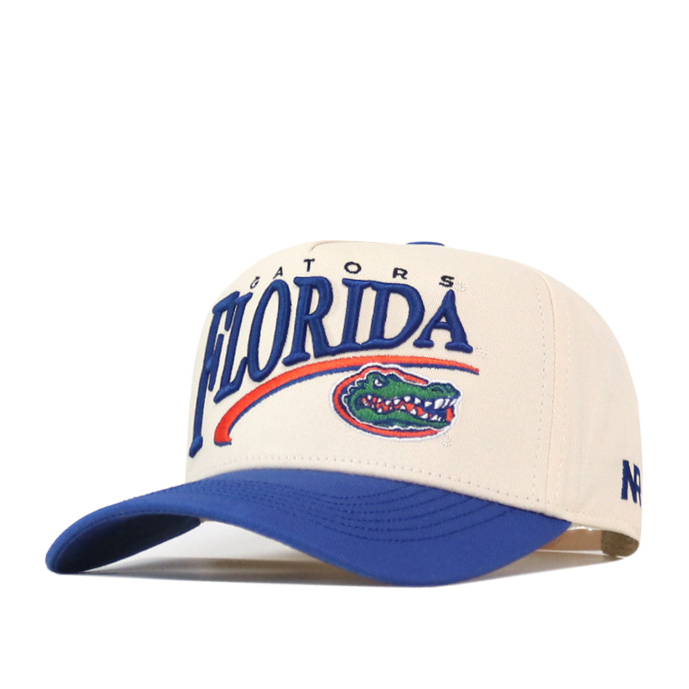 The No Rivals Florida Gators Stride Hat is a white and blue structured fit cap featuring FLORIDA and a green alligator logo embroidered on the front to represent the Florida Gators sports team. Made from high-quality cotton, this hat offers a comfortable fit with its adjustable snap back closure.