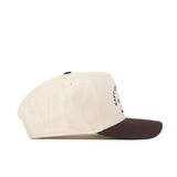 The No Rivals ECU Pirates Outlaw Hat - Classic is a cream-colored baseball cap with a dark brown brim, made from high quality cotton and featuring a snap back adjustment. It is shown from the side on a white background.