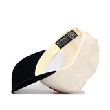 The Scheels Longhorn Hat - Black is shown turned inside out, displaying beige and black colors, interior labels, stitching details, a structured fit with a black brim, and a QR code on one of the inside tags.