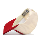 A red and light cream Utah Utes Stride Hat by No Rivals is displayed upside down, revealing the interior details such as tags, stitching, and embroidered logos. The snapback cap features a red brim and showcases its officially licensed design.