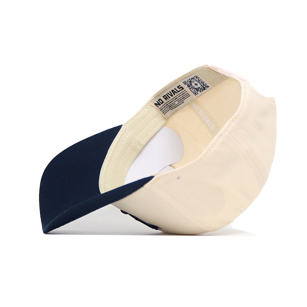 The Nevada Logo Patch Hat by No Rivals features a beige and navy blue design, side view showing the inside crown and brim, visible brand label, QR code on the headband, and classic snap back closure.