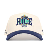 The No Rivals Rice Ballpark Hat is a white cap with a blue brim, showcasing an embroidered "RICE Owls" and "Est. 1912" logo on the front, set against a green and gold shield.