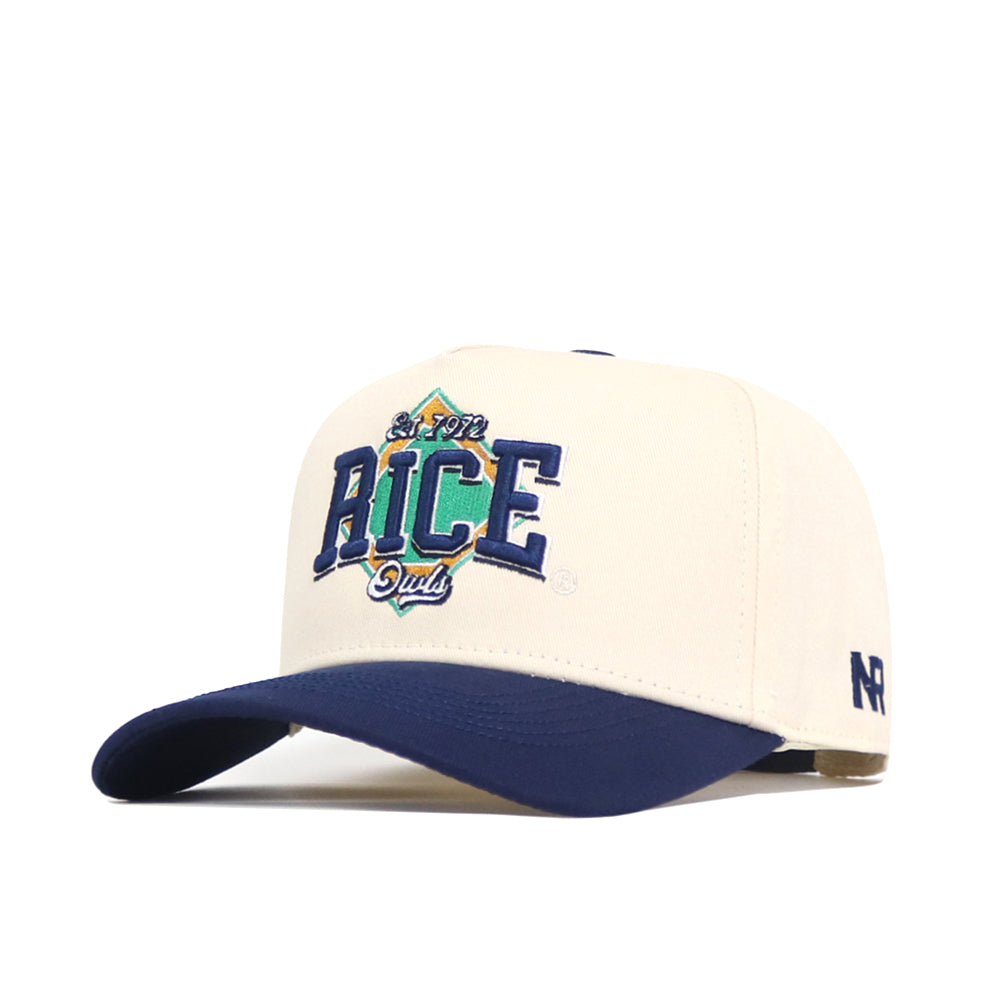 The No Rivals Rice Ballpark Hat is cream-colored with a navy curved brim, featuring an embroidered "San Fran RICE Dual" logo in blue, green, and yellow on the front and a small “NR” logo on the side.