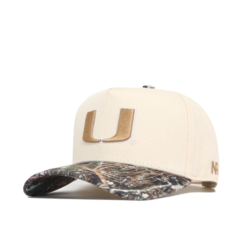 The Miami Camo Connector Hat by No Rivals features a structured fit in high-quality cotton, a beige crown with a large gold U embroidered on the front, and a camouflage-patterned curved brim.