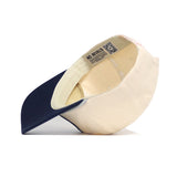 A close-up side view of the officially licensed No Rivals Penn State Seal Hat, shown upside-down to display the interior details and labels, featuring a dark blue brim and a beige crown.