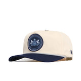 The No Rivals Penn State Seal Hat is a cream snapback with a navy brim, featuring a circular PSU crest on the front and "N" on the side. Made from quality cotton and officially licensed for authenticity.