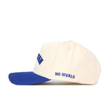 The Right Side Up CREIGHTON Hat by No Rivals features cream cotton-canvas, a blue brim, "NO RIVALS" embroidered on the side in blue, and a structured fit with classic snapback closure.