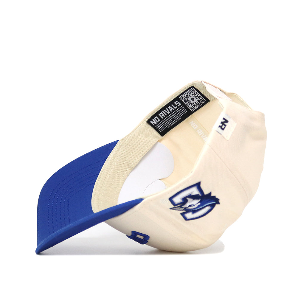 The Right Side Up CREIGHTON Hat by No Rivals features classic cream and blue cotton-canvas, a structured snapback fit, an inside NO RIVALS label, and an embroidered cartoon-style blue jay logo on the front.