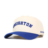 The Right Side Up CREIGHTON Hat by No Rivals features a cream cotton-canvas design with a blue brim, blue "CREIGHTON" embroidery on the front, and partial "NO RIN" branding visible on the side.