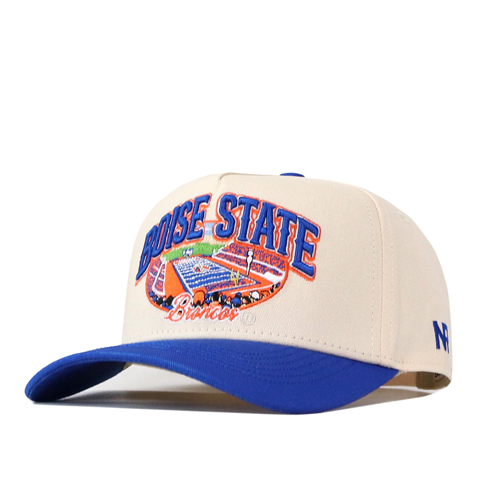 Show your Boise State pride with the No Rivals Boise State Broncos Stadium Hat, a beige and blue snapback featuring bold embroidered logos. “Boise State Broncos” is stitched above a detailed football stadium image on the front, while an “N” is sewn onto the left side. The blue underbrim adds a classic touch—perfect for elevating your gameday look.