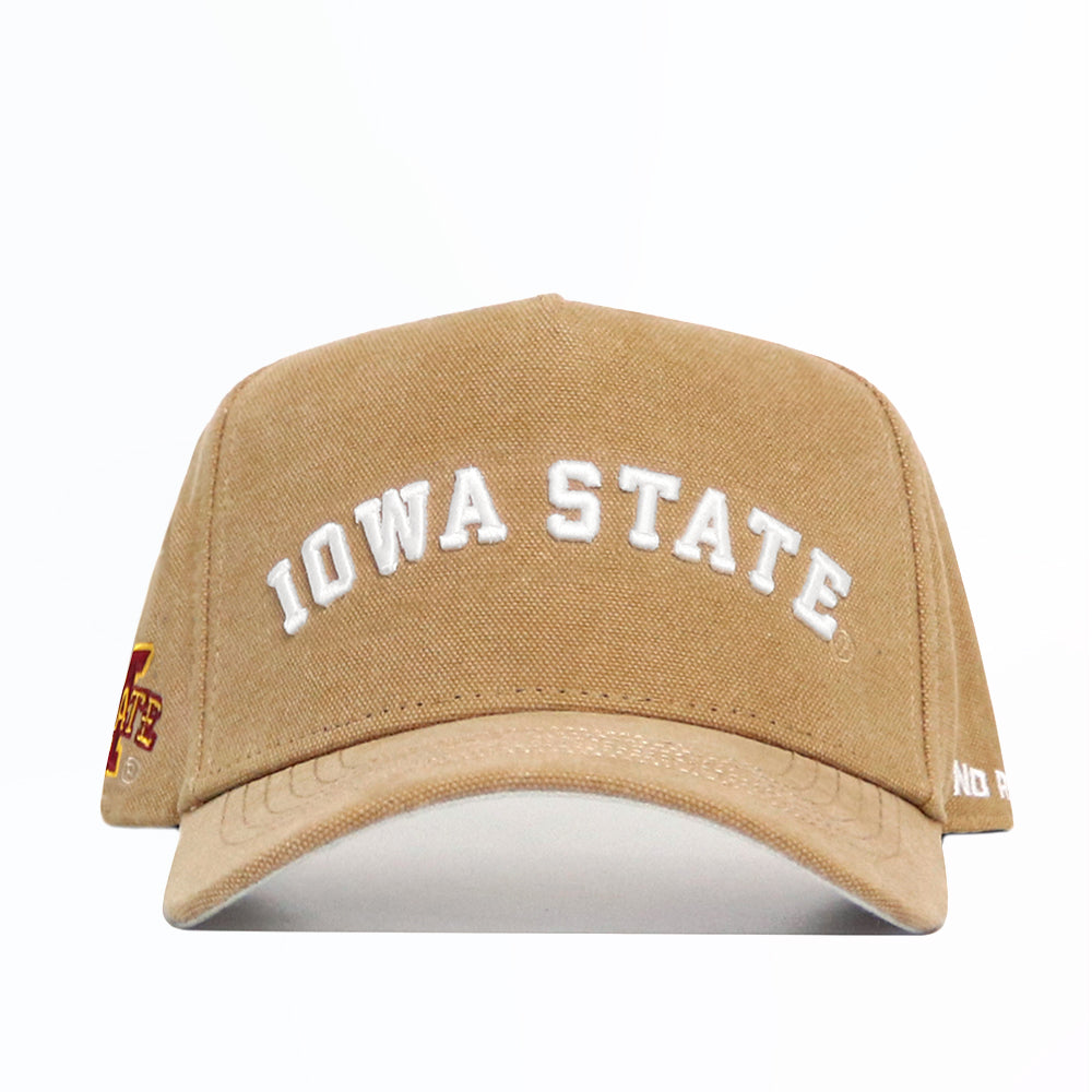 The Iowa State Rustic Hat by No Rivals is a tan cotton canvas cap with "IOWA STATE" embroidered in white, a curved brim, snapback closure, and a small red and yellow logo on the left side. The background is plain white.