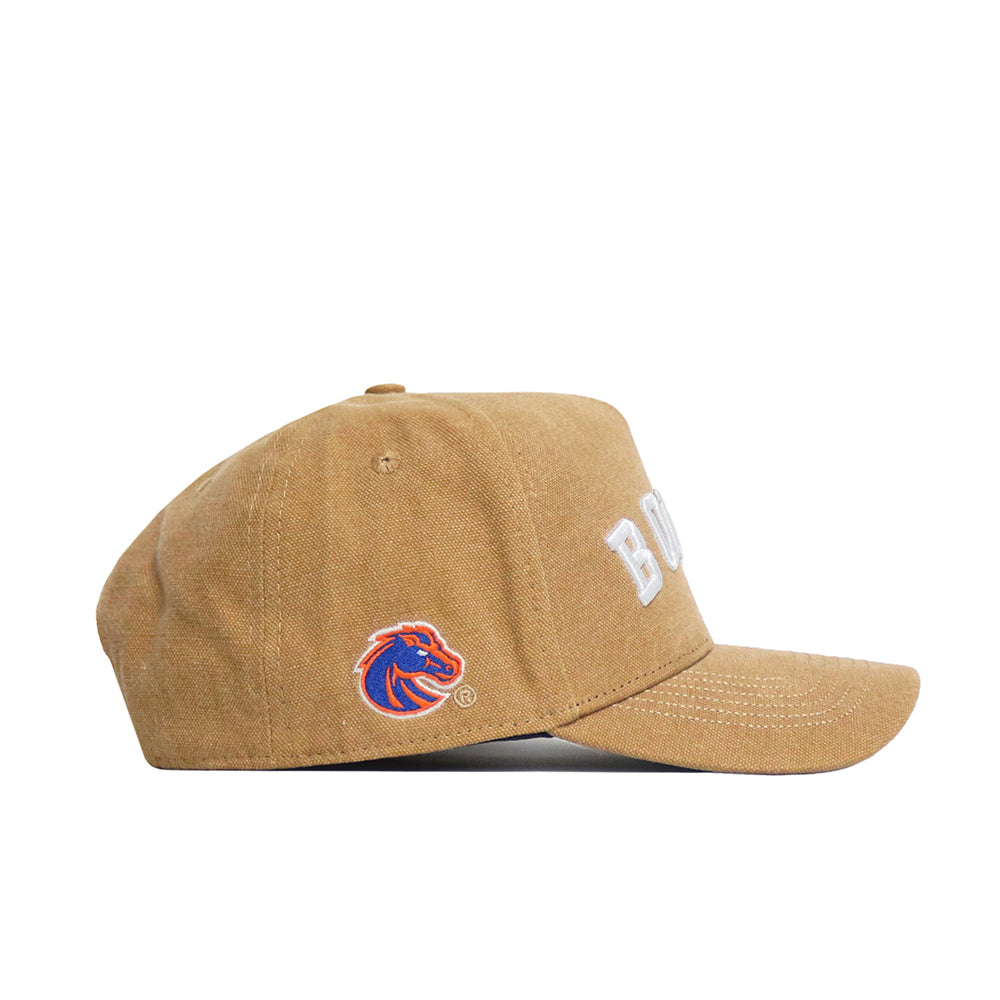 The No Rivals Boise State Rustic Hat is a tan cotton canvas snapback with "BOISE" embroidered in white on the front and a blue and orange horse logo on the side, shown from the left to highlight its structured fit.