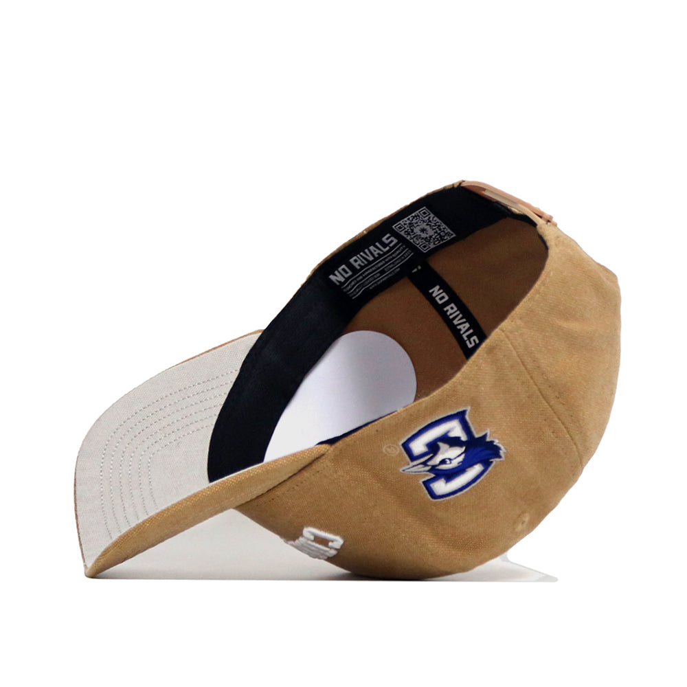 The Creighton Rustic Hat by No Rivals is a brown and white cotton canvas baseball cap, shown on its side with an embroidered blue and white horse logo, the number 3, and "NO RIVALS" text inside the snapback band.