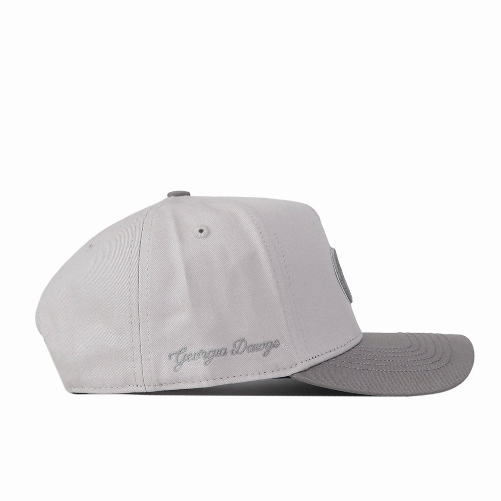 A side view of the Georgia Graphite Hat by No Rivals, this light gray snapback cap features a flat, darker gray brim and an embroidered “Georgia Dawgs” cursive logo above the ear. It’s the perfect accessory to complete your gameday look.