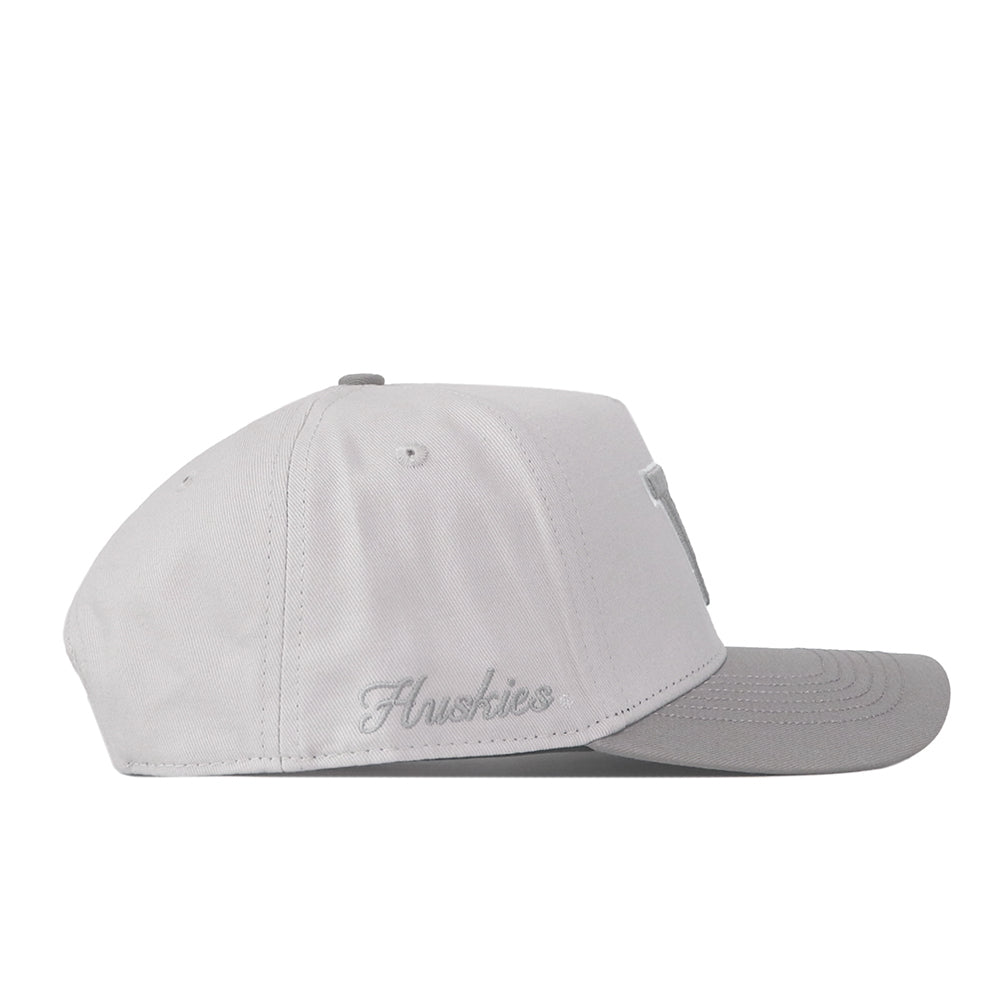 The No Rivals Washington Huskies Graphite Hat is shown from a side view on a white background. This light gray cap features an embroidered logo, “Huskies” stitched in cursive on the side, and a snap back closure—perfect for your next gameday fit.