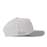 The No Rivals Washington Huskies Graphite Hat is shown from a side view on a white background. This light gray cap features an embroidered logo, “Huskies” stitched in cursive on the side, and a snap back closure—perfect for your next gameday fit.