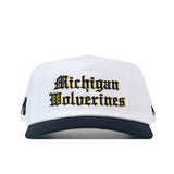 No Rivals Michigan Old English Rope Hat, a white 5-panel hat with a navy blue brim, yellow Old English Michigan Wolverines embroidery on the front, and an adjustable snap back.