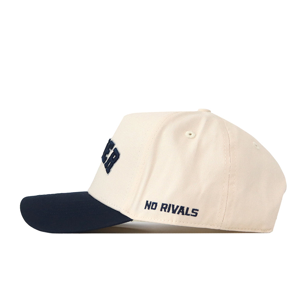 The Right Side Up Xavier Hat - Classic by No Rivals is a cream-colored snapback baseball cap with a black brim, featuring the embroidered words “NO RIVALS” in bold black thread on the side—an essential for any gameday fit.