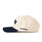 The Right Side Up Xavier Hat - Classic by No Rivals is a cream-colored snapback baseball cap with a black brim, featuring the embroidered words “NO RIVALS” in bold black thread on the side—an essential for any gameday fit.