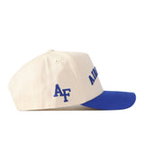 The Right Side Up Air Force Hat - Classic Colors by No Rivals is a cream-colored snapback cap with a royal blue brim. The side displays officially licensed blue “AF” initials, while the front features partially visible blue embroidered logo text.
