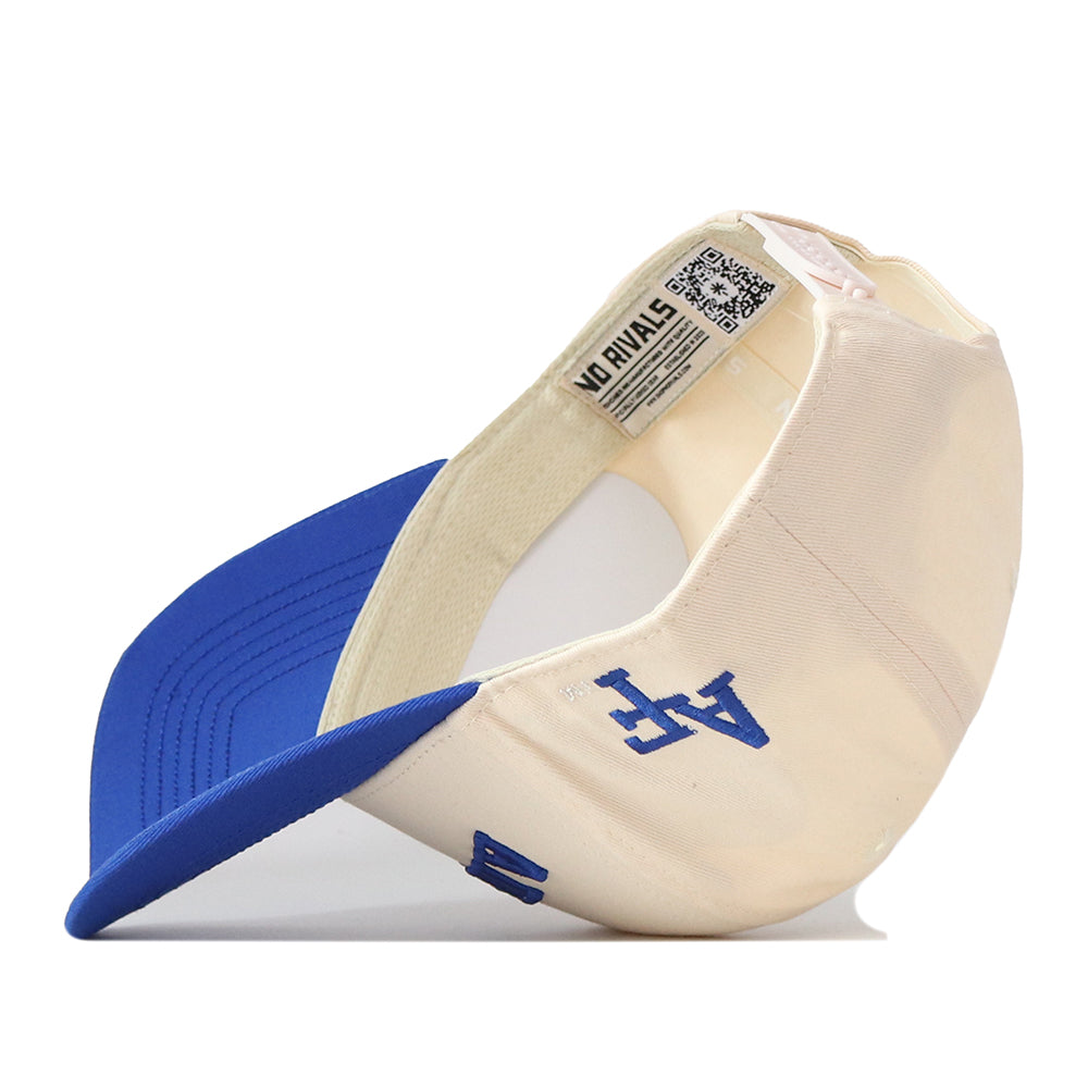 The Right Side Up Air Force Hat - Classic Colors by No Rivals features a cream and blue snapback design with an LA logo embroidered on the side. Shown turned upside down to display the inside tag and blue brim, this officially licensed cap combines classic style with authentic No Rivals details.