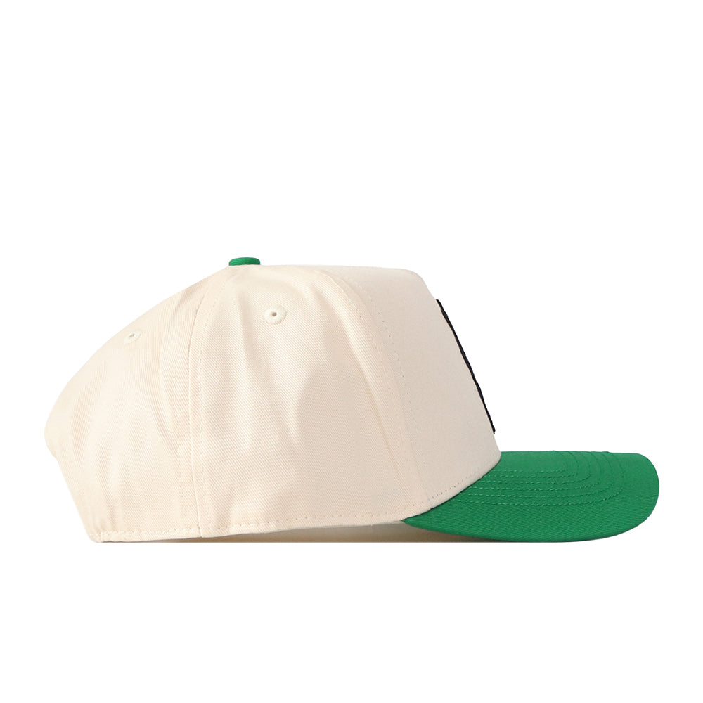 The No Rivals UNT Desert Scrappy Logo Hat is a cream-colored cotton blend baseball cap featuring a green brim and patch embroidery, shown from the side against a white background.