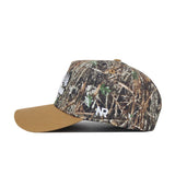 The Scheels Camo Explorer Hat features a brown suede bill, green-brown-tan camo crown, and white "NR" embroidery on the side. Enjoy a structured fit for style and durability.