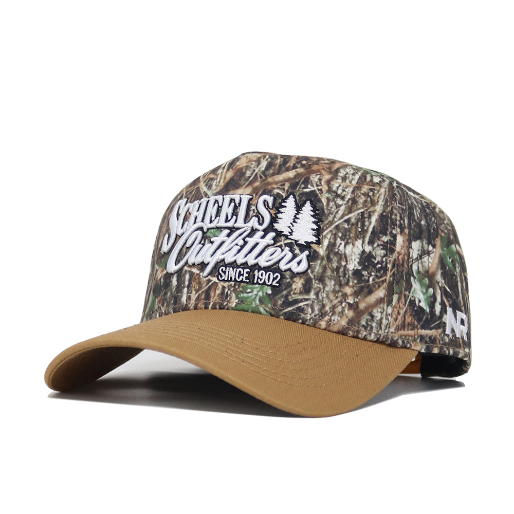 The Scheels Camo Explorer Hat is a structured fit camo baseball cap made from quality cotton, featuring a tan brim, white "Scheels Outfitters Since 1902" embroidery with tree graphics, an "NR" side logo, and an adjustable snapback closure.