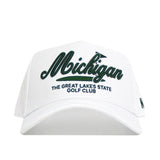 The Michigan Clubhouse Hat by No Rivals is a structured white baseball cap with "Michigan" in bold green script, "The Great Lakes State Golf Club" in small black letters, a comfy polyester-cotton blend, and an adjustable snapback closure.