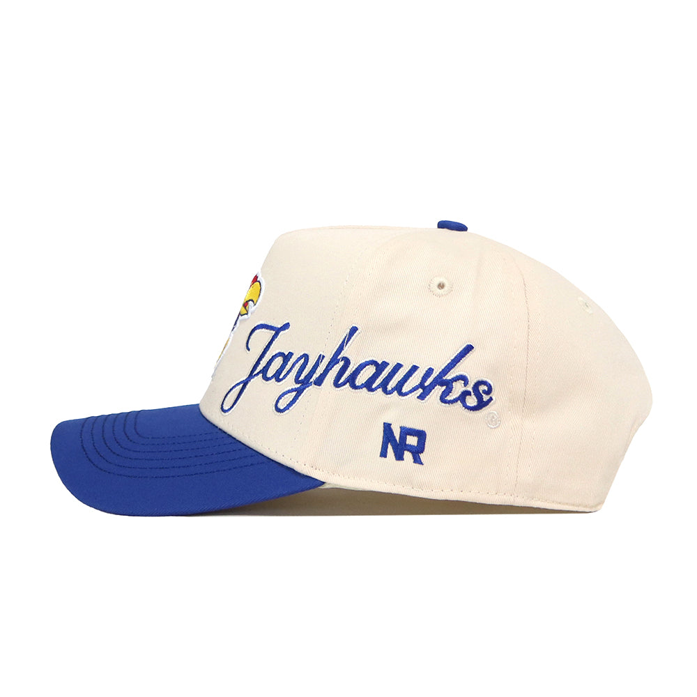 The Kansas Jayhawks Halftime Hat by No Rivals is a white snapback baseball cap with a blue brim, officially licensed and featuring "Jayhawks" embroidered in blue script on the side with the NR logo beneath it. Finely detailed, embroidered logos add a classic touch to this standout accessory.