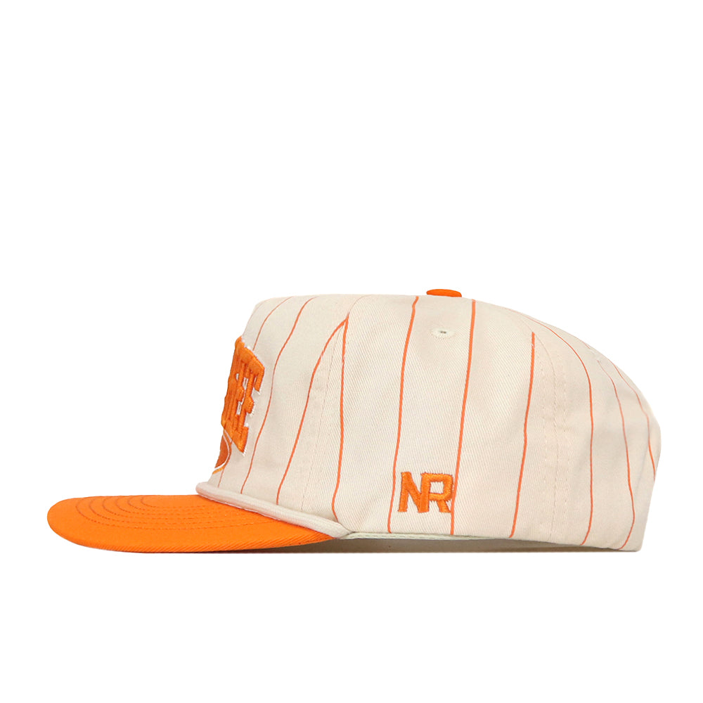 The Tennessee Pinstripe Traditions Hat by No Rivals features a cream-colored design with thin orange vertical stripes, an orange flat brim, a large embroidered orange logo on the front, and orange “NR” initials on the side. Crafted from a soft cotton blend with a snap back closure for an adjustable fit, this cap is displayed in a left side profile view.