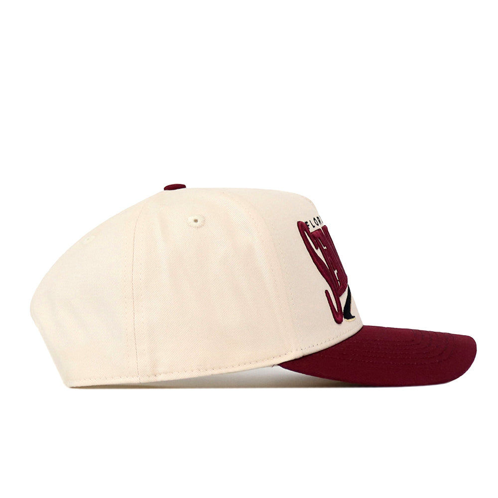 The No Rivals Florida State Seminoles Stride Hat is a cream baseball cap with a maroon brim, shown from the side. Made from high quality cotton, this structured snapback features embroidered maroon text and design details on the front panel.