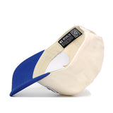 The Creighton Triangle Game Cap Hat by No Rivals is shown upside down, revealing its cream color, blue brim, and an inside label with the NO RIVALS brand name and a QR code.