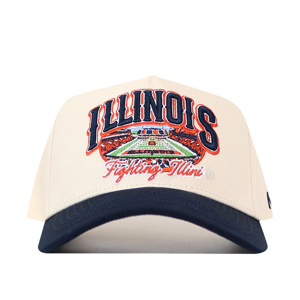 The No Rivals Illinois Fighting Illini Stadium Hat is a beige and navy snapback featuring “ILLINOIS” and “Fighting Illini” embroidered above a detailed football stadium graphic, with officially licensed embroidered logos for an authentic look.