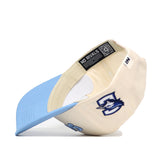 The Upside Down JAYS Hat - Creighton by No Rivals is a cream and light blue snapback cap with a wolf logo on the front panel and under the visor. Inside, it features a NO RIVALS tag, QR code, and structured fit for comfort.