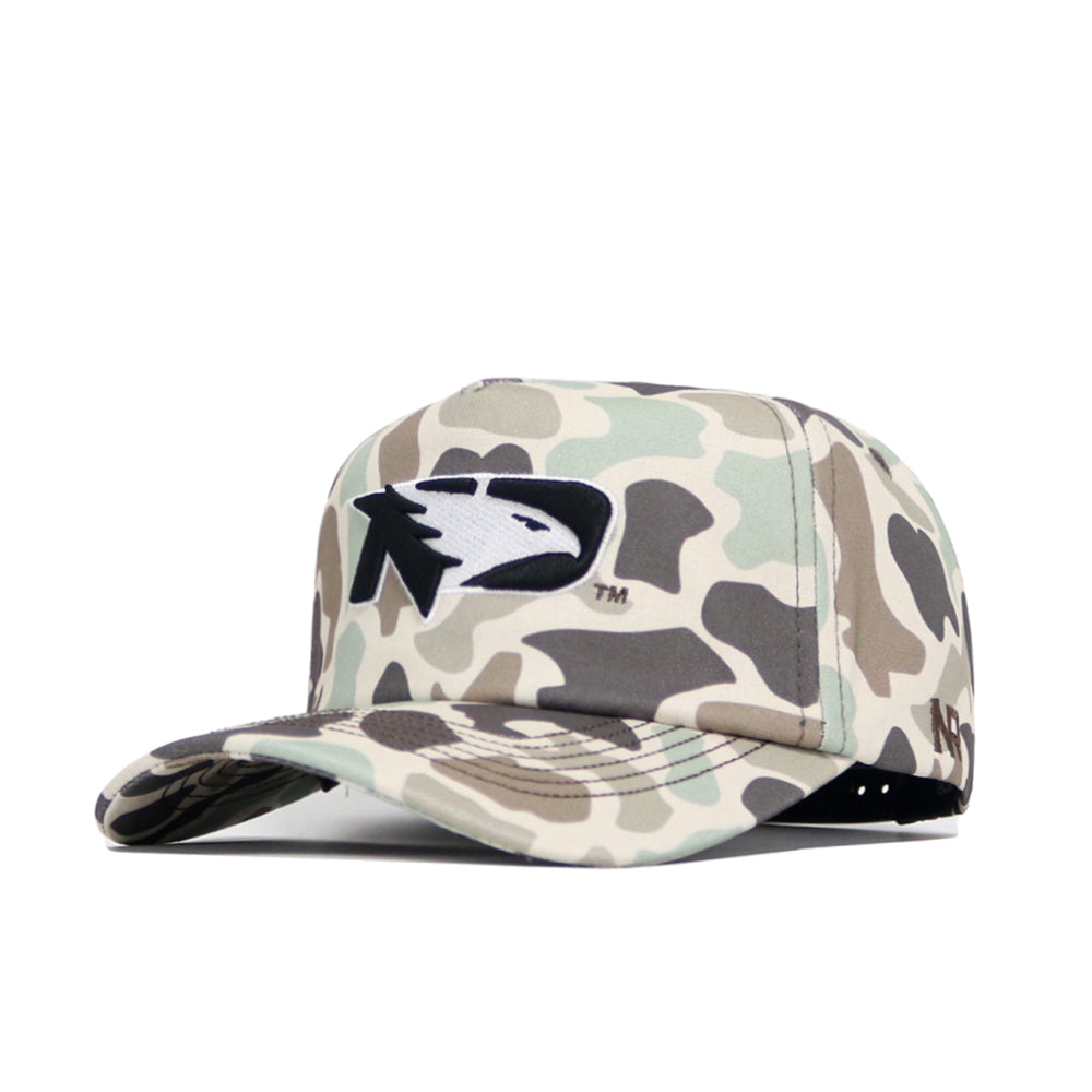 The North Dakota Huntsman Hat by No Rivals is a 5-panel duck camo baseball cap with a black and white eagle head logo, flat bill, and adjustable strap.