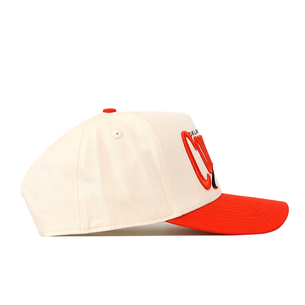 A side view of the No Rivals Oklahoma State Cowboys Stride Hat shows its cream-colored snapback design with a vibrant red brim and top button. Red and black embroidered logos are partially visible on the front, making this hat a classic pick for your gameday outfit.