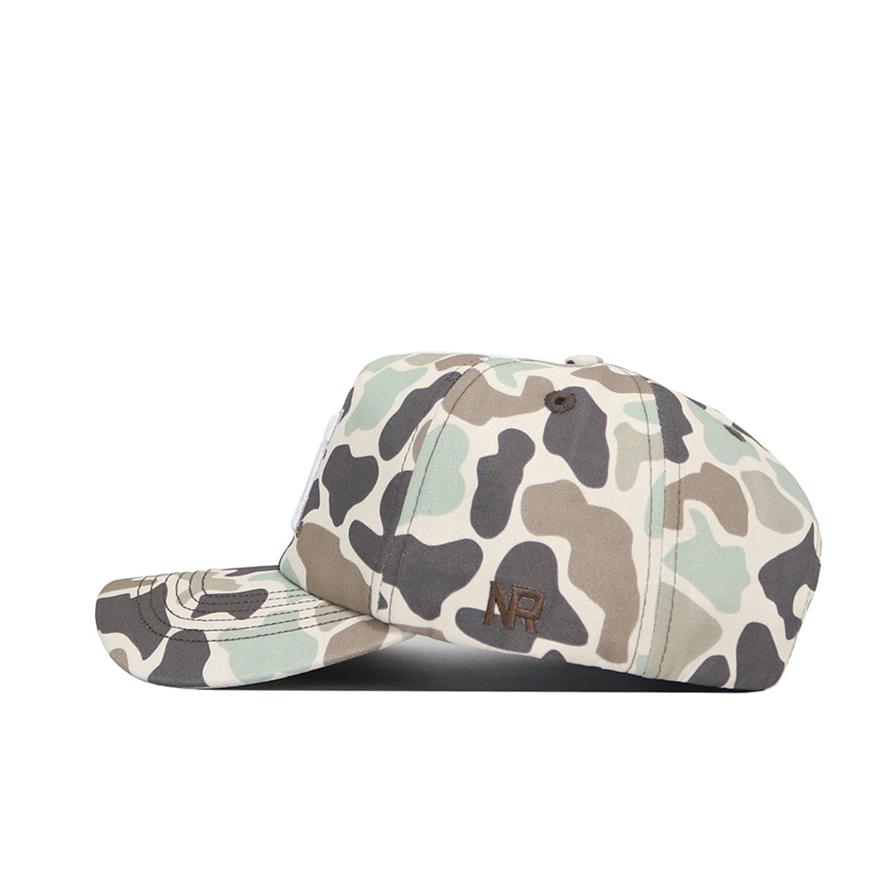 A side view of the Nebraska Huntsman Hat by No Rivals, showing its green, brown, and beige camo pattern. This classic 5-panel cap has a curved brim and a small dark NR logo on the side.