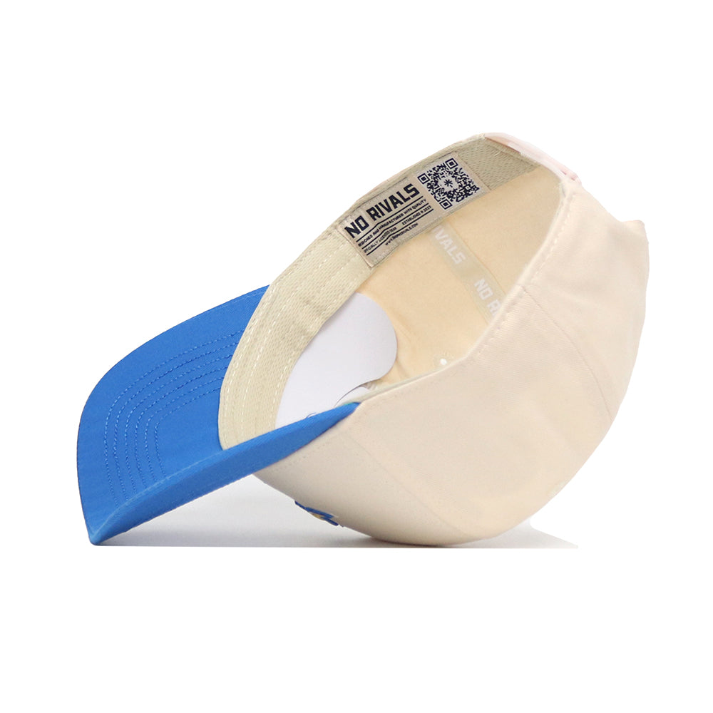 The South Dakota State Logo Patch Hat by No Rivals is a structured snapback with a blue brim, beige crown, visible stitching, sweatband, and "NO RIVALS" printed on the inner band.