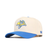 The South Dakota State Logo Patch Hat by No Rivals is a cream structured baseball cap with a blue brim, featuring an embroidered yellow and blue jackrabbit logo on the front and NR letters on the side—perfect for any occasion.