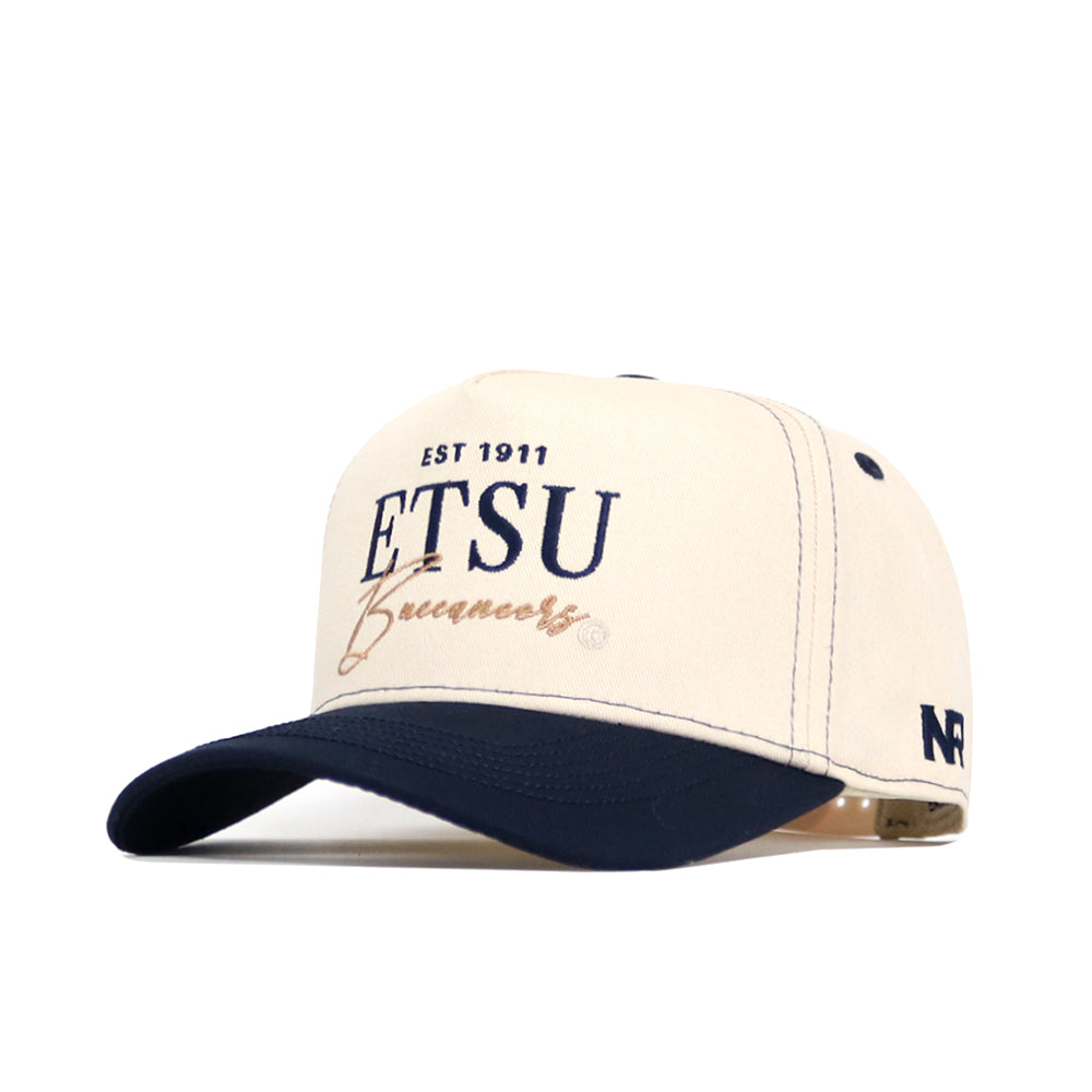 The ETSU Vintage Hat by No Rivals is a cream and navy snapback with "EST 1911 ETSU Buccaneers" on the front and "NR" on the side. This structured cap features a curved brim, ventilation holes, and is made from high-quality cotton for comfort.