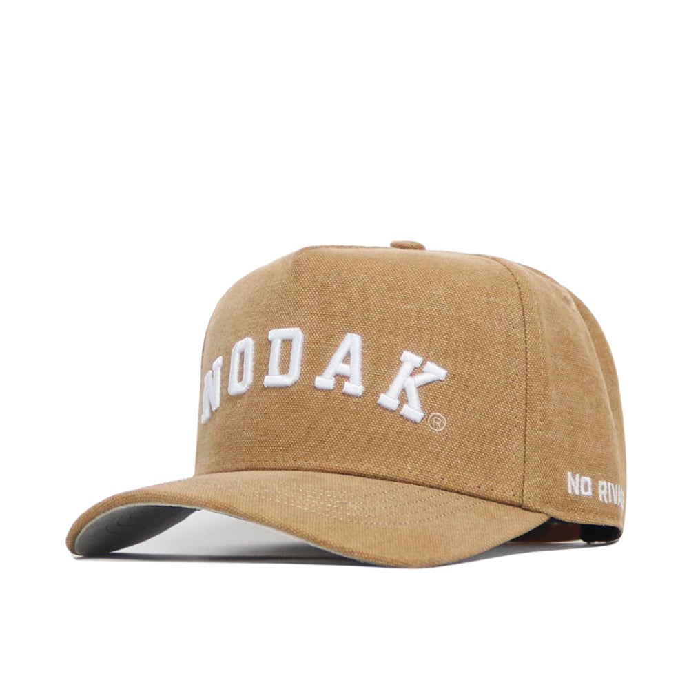 The North Dakota Rustic Hat by No Rivals is a tan cotton canvas cap with "NODAK" embroidered in large white letters on the front and "NO RIV" on the side of the brim. Features a classic structured fit for comfort and lasting style.