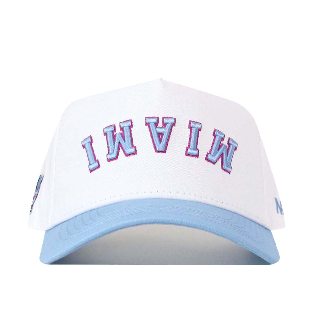 The FIU Panthers | Upside Down Miami Hat - Whiteout by No Rivals features a white design with a light blue brim and “MIAMI” embroidered in upside down blue and pink letters on the front.