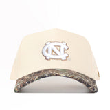 The No Rivals UNC Camo Connector Hat features a beige snapback design, the University of North Carolina interlocking NC logo on the front, a camo-patterned brim, and is crafted from high-quality cotton for structure and style.