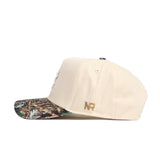 The No Rivals UNC Camo Connector Hat is a beige snapback cap crafted from premium cotton, featuring a camouflage-patterned brim and gold NR initials on the side, shown in side profile against a white background.