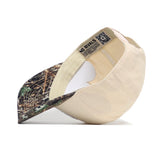 The UNC Camo Connector Hat by No Rivals is a beige, structured baseball cap made from high-quality cotton, with a curved brim and camouflage pattern. Shown from the side, the inner band features "NO RIVALS" text.