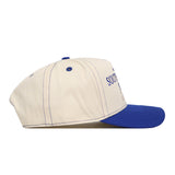 The No Rivals South Dakota State Vintage Hat, shown from a side view against a white background, features a cream color with a blue brim, blue stitching, and an officially licensed blue embroidered logo on the front.