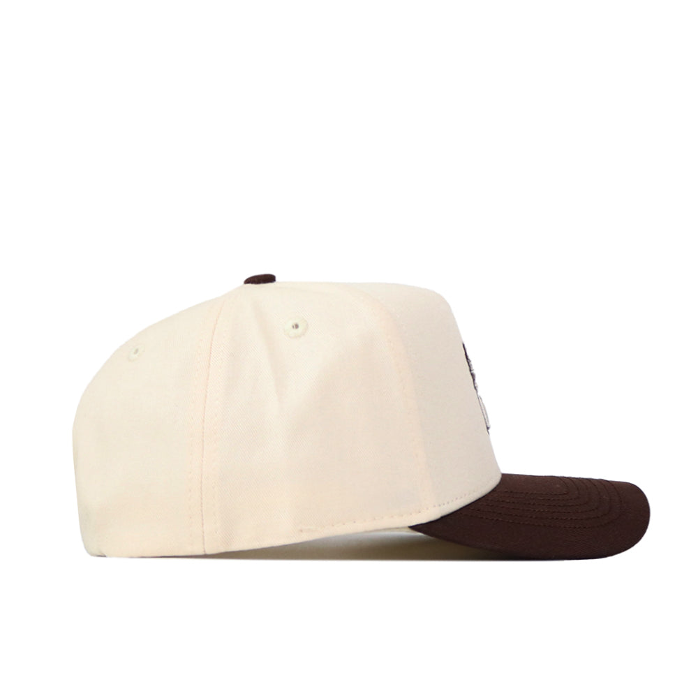 The No Rivals Creighton Espresso Hat is a cream snapback made of high-quality cotton with a dark brown curved visor, shown from the side on a white background.